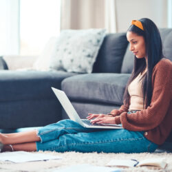 Young woman researching student loan repayment on a laptop in a living room.