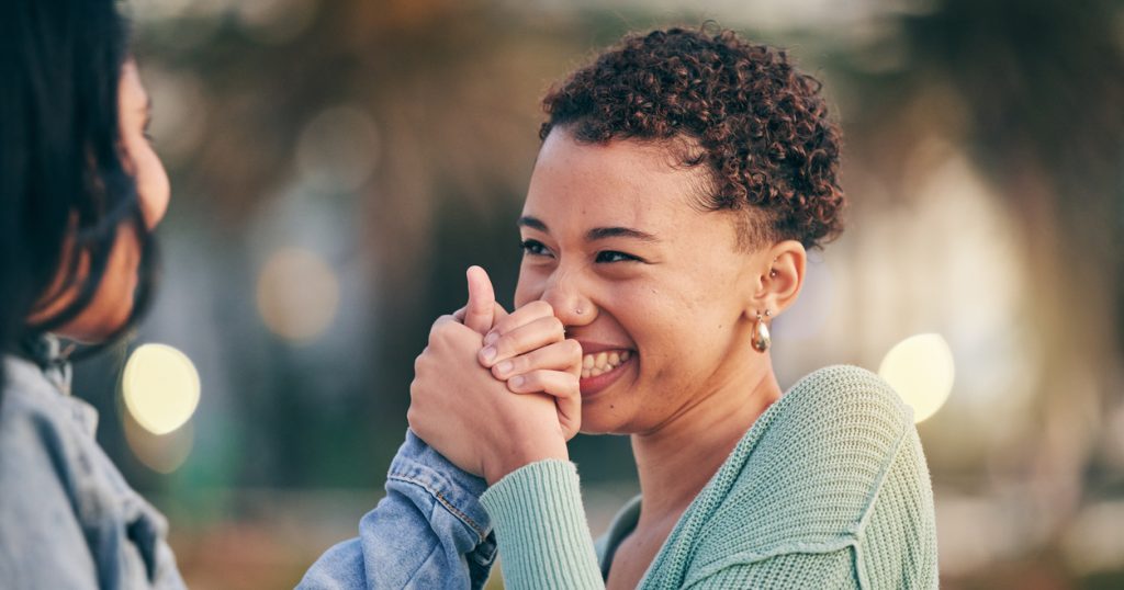 A couple holds hands as they smile at each other lovingly.